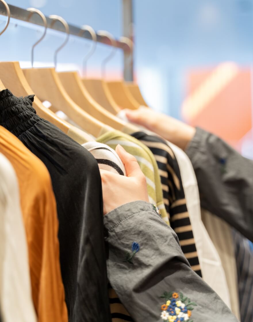 ハンガーラックに並んでいる洋服を手で押さえている写真